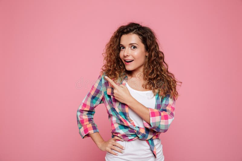 Verraste vrouw die op exemplaarruimte richten over roze stock afbeelding Verraste vrouw die op exemplaarruimte richten over roze stock afbeelding