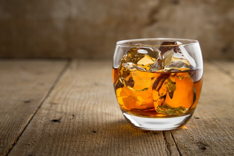 Verre d'eau-de-vie fine de whisky écossais avec de la glace sur la surface rustique de baril de table en bois de barre photos libres de droits Verre d'eau-de-vie fine de whisky écossais avec de la glace sur la surface rustique de baril de table en bois de barre photos libres de droits