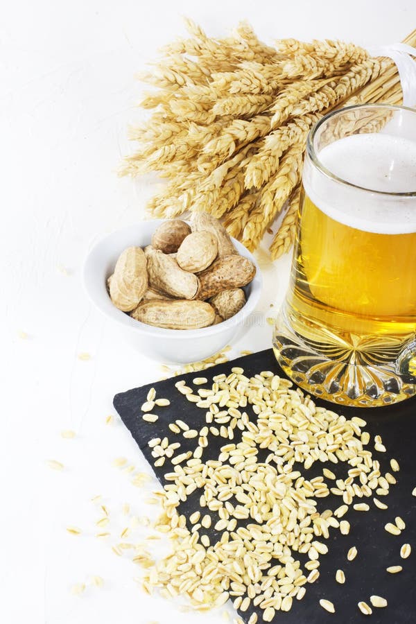 Verre de bière froide avec des frites et des arachides sur le fond blanc image libre de droits Verre de bière froide avec des frites et des arachides sur le fond blanc image libre de droits