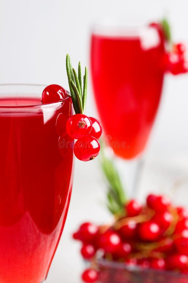 Glass of redcurrant wine drink juice decorated with rosemary and berries on light concrete background. Vertical orientation, place for copy space. Glass of redcurrant wine drink juice decorated with rosemary and berries on light concrete background. Vertical orientation, place for copy space.