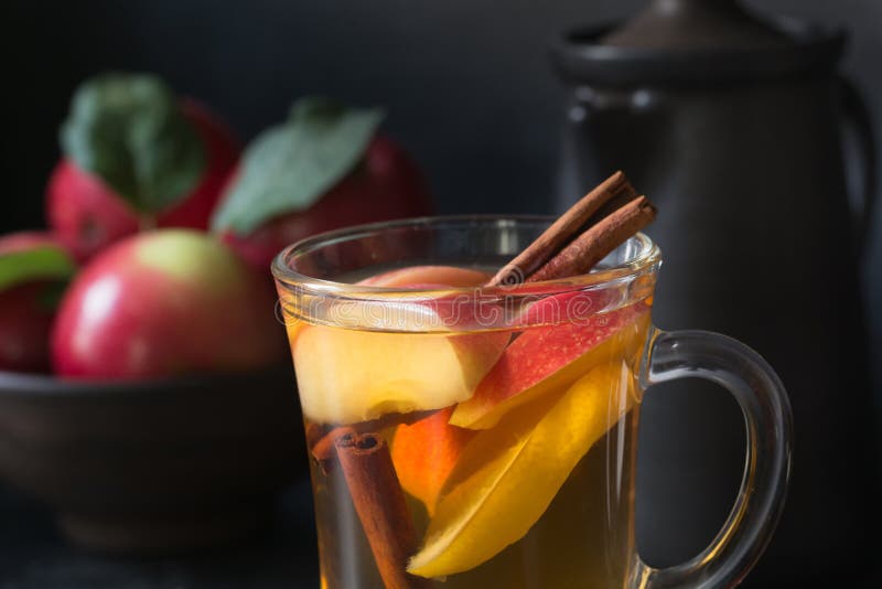 Verre de thé avec la pomme et la cannelle de citron, épicée, coupé en tranches sur le conseil noir D'automne toujours durée photo libre de droits Verre de thé avec la pomme et la cannelle de citron, épicée, coupé en tranches sur le conseil noir D'automne toujours durée photo libre de droits