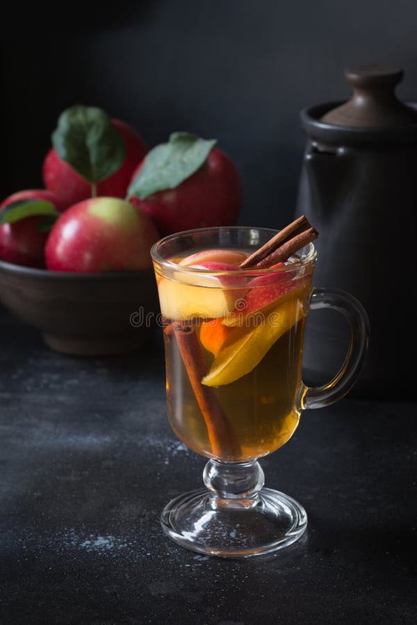 Verre de thé avec la pomme et la cannelle de citron, épicée, coupé en tranches sur le conseil noir D'automne toujours durée images libres de droits Verre de thé avec la pomme et la cannelle de citron, épicée, coupé en tranches sur le conseil noir D'automne toujours durée images libres de droits