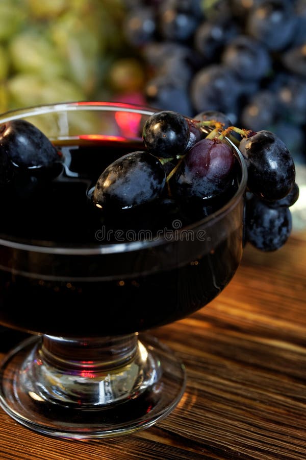 Verre large accompagné de vin, de teinture ou de jus faits maison à côté de raisins rouges et noirs sur fond de lumières festives image stock Verre large accompagné de vin, de teinture ou de jus faits maison à côté de raisins rouges et noirs sur fond de lumières festives image stock