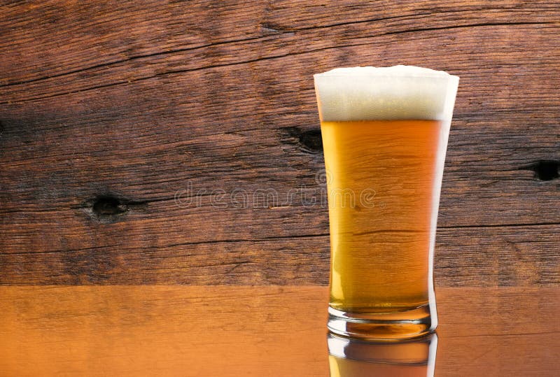 Gorgeous glass of delicious beer with a barn wood background and a reflection. Gorgeous glass of delicious beer with a barn wood background and a reflection.