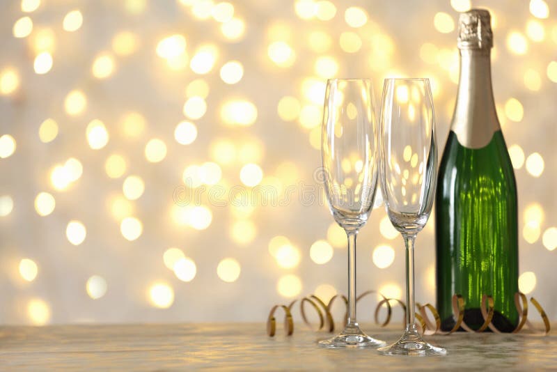 Verres et bouteille vides de champagne sur la table contre les lumi?res brouill?es image libre de droits Verres et bouteille vides de champagne sur la table contre les lumi?res brouill?es image libre de droits