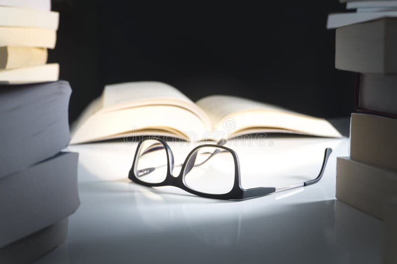 Verres et livre ouvert sur la table entourée par la littérature photographie stock Verres et livre ouvert sur la table entourée par la littérature photographie stock