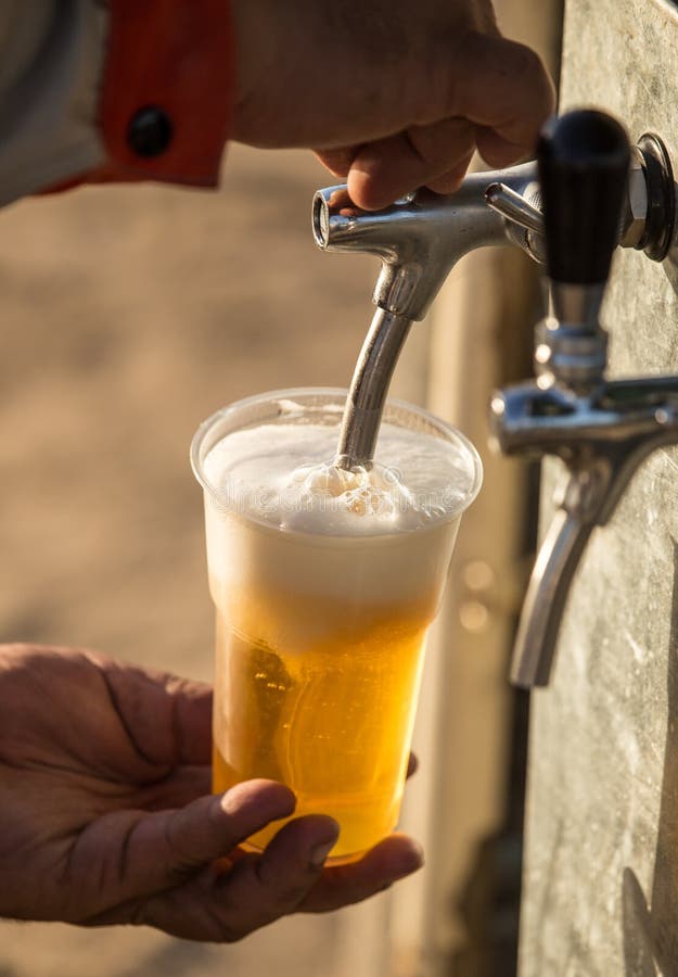 Vers bier in een plastic kop in de hand royalty-vrije stock fotografie Vers bier in een plastic kop in de hand royalty-vrije stock fotografie