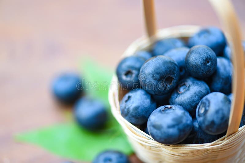 Vers bosbessenfruit in mand en groene bladeren op houten achtergrond stock fotografie Vers bosbessenfruit in mand en groene bladeren op houten achtergrond stock fotografie