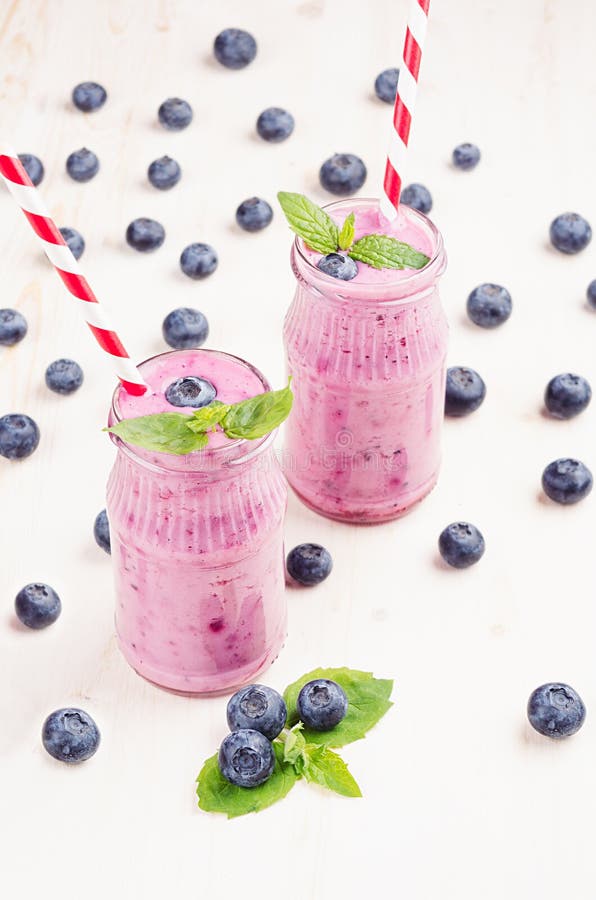Vers gemengd violet bosbessenfruit smoothie in glaskruiken met stro, muntbladeren, bessen witte Houten raadsachtergrond royalty-vrije stock afbeelding Vers gemengd violet bosbessenfruit smoothie in glaskruiken met stro, muntbladeren, bessen witte Houten raadsachtergrond royalty-vrije stock afbeelding