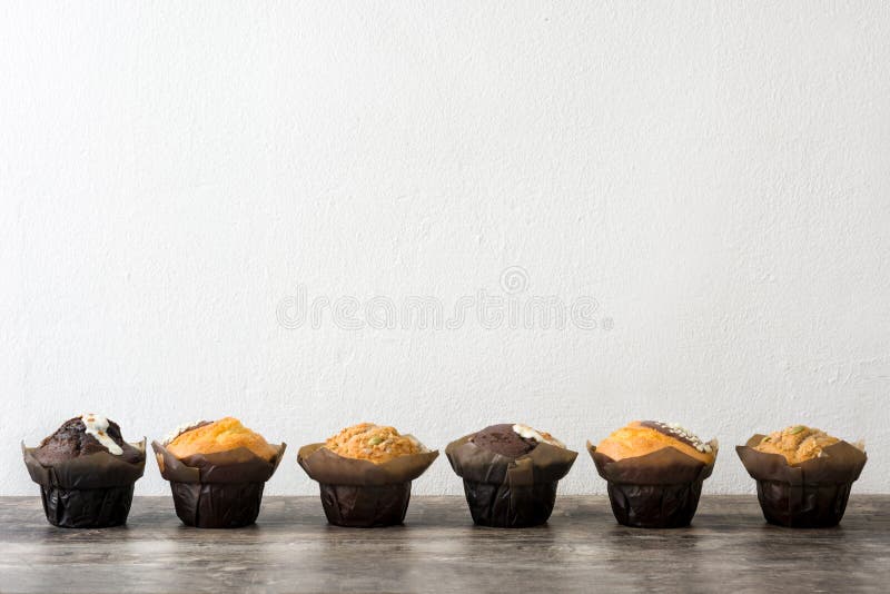 Verscheidenheid van muffins op een houten lijst en een witte muur stock afbeeldingen Verscheidenheid van muffins op een houten lijst en een witte muur stock afbeeldingen