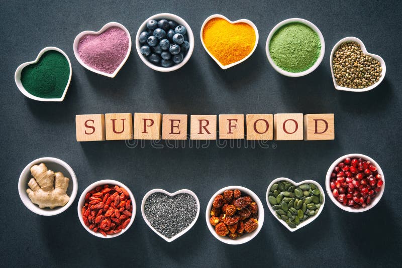 Various colorful superfoods as acai powder, turmeric, matcha green tea, spirulina, quinoa, pumpkin seeds, blueberry, dried goji berries, cape gooseberries, raw cocoa, hemp seeds and other in bowls on dark background. Various colorful superfoods as acai powder, turmeric, matcha green tea, spirulina, quinoa, pumpkin seeds, blueberry, dried goji berries, cape gooseberries, raw cocoa, hemp seeds and other in bowls on dark background