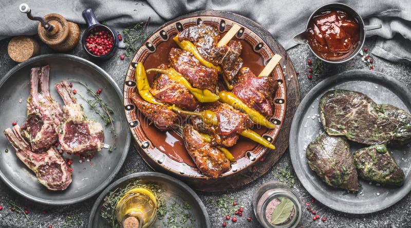 Verschiedenes Fleisch für Grill: Fleischaufsteckspindeln, Lamm beansprucht Rippen und marinierte Steaks auf rustikalem Küchentisc stockfotografie