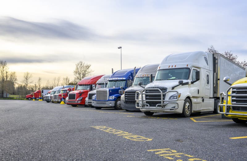 Verschillende grote vrachtwagens met opleggers op rij op parkeerplaats voor vrachtwagens met gereserveerde plaatsen voor vrachtwag