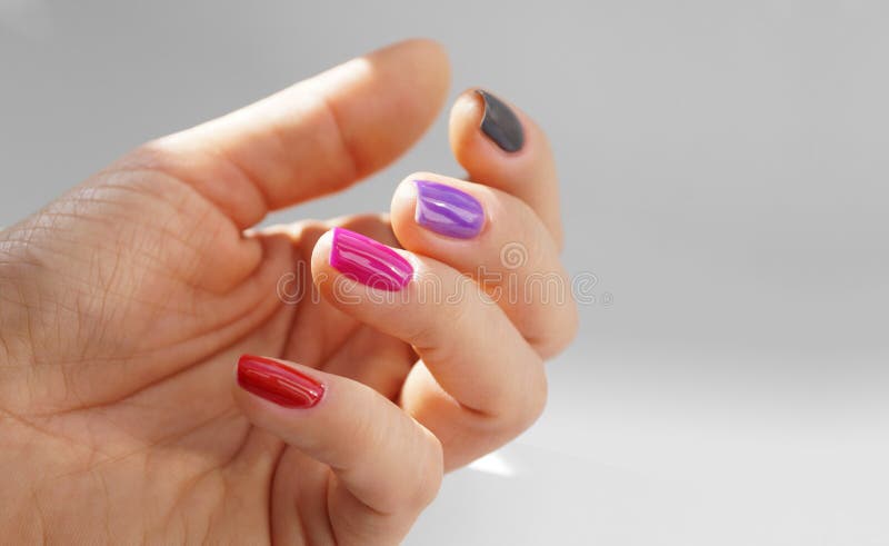 Feminine hand with painted nails, each in a different color. Feminine hand with painted nails, each in a different color