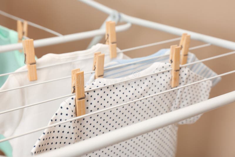 Verschillende leuke baby die onesies op waslijn beige achtergrond hangen, close-up Rijp Vrouw die Wasserij doet stock fotografie Verschillende leuke baby die onesies op waslijn beige achtergrond hangen, close-up Rijp Vrouw die Wasserij doet stock fotografie