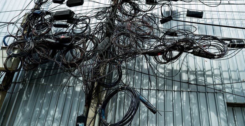 Verschlungene elektrische Drähte und verschlungene Kommunikationsleitungen an städtischen Strommasten bilden ein chaotisches Netzw stockbild