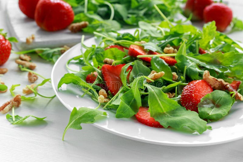 Verse aardbeisalade met arugula op witte plaat royalty-vrije stock afbeeldingen