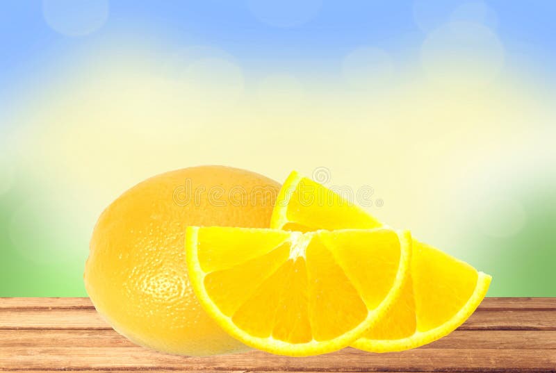 Fresh lemon and slices on the wooden table over nature background. Fresh lemon and slices on the wooden table over nature background