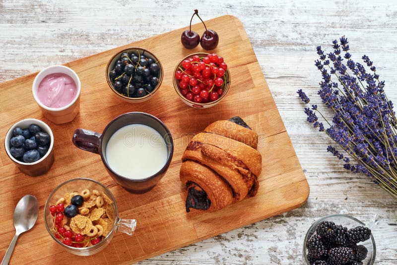 Verse croissant, bessen, yoghurt, cornflakes en kop van melk op een houten lijst stock foto Verse croissant, bessen, yoghurt, cornflakes en kop van melk op een houten lijst stock foto