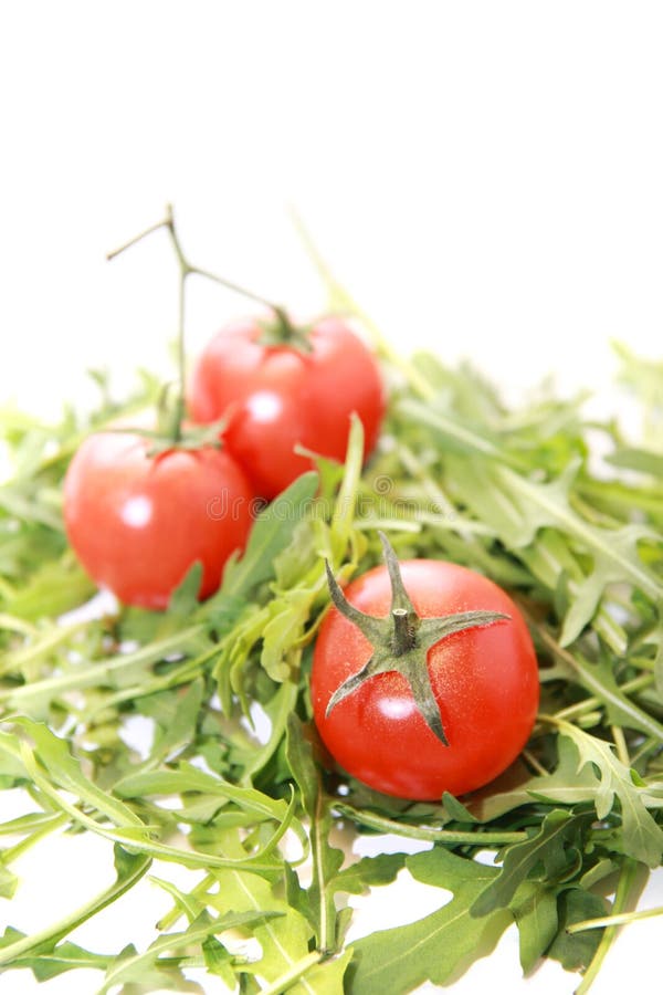 Verse die rucola met tomaten op wit worden geïsoleerd. stock afbeelding Verse die rucola met tomaten op wit worden geïsoleerd. stock afbeelding