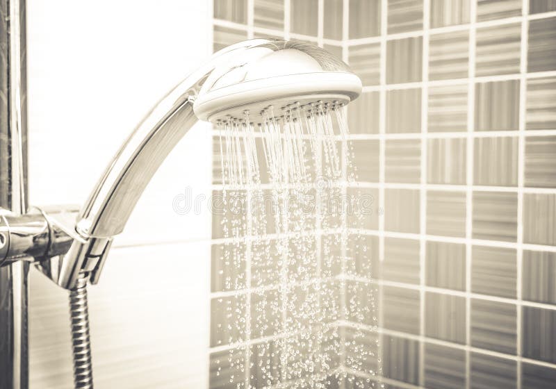 Verse douche waar Water die van douchehoofd en tapkraan lopen in moderne badkamers met oranje muur stock foto's Verse douche waar Water die van douchehoofd en tapkraan lopen in moderne badkamers met oranje muur stock foto's