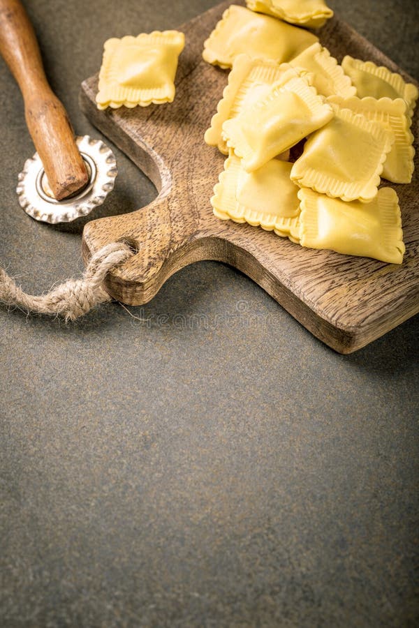 Fresh homemade italian stuffed square pasta ravioli on wooden cutting board. Healthy food concept, gluten free. Fresh homemade italian stuffed square pasta ravioli on wooden cutting board. Healthy food concept, gluten free.