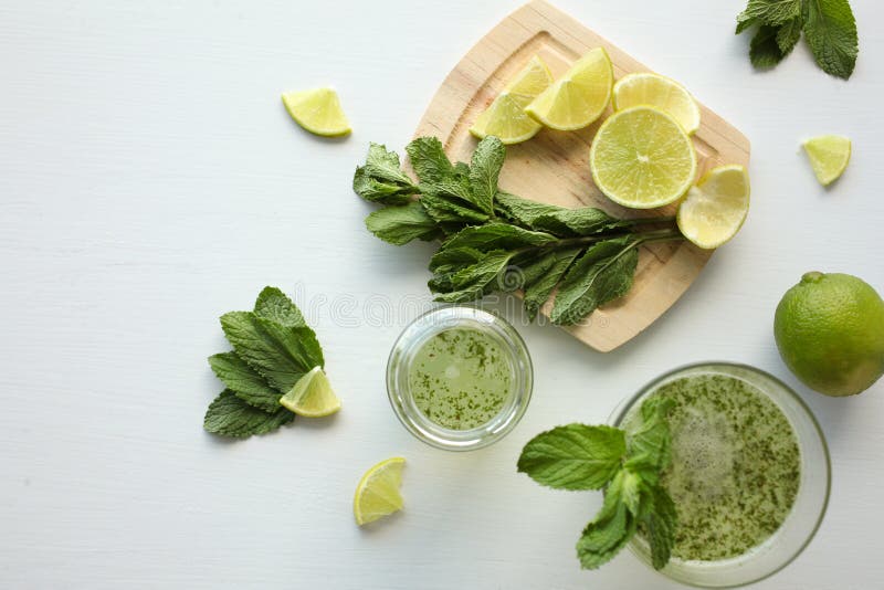 Verse eigengemaakte limonade met citroen, kalk en munt in een glas op witte achtergrond en ingrediënten die op de lijst leggen stock afbeeldingen Verse eigengemaakte limonade met citroen, kalk en munt in een glas op witte achtergrond en ingrediënten die op de lijst leggen stock afbeeldingen