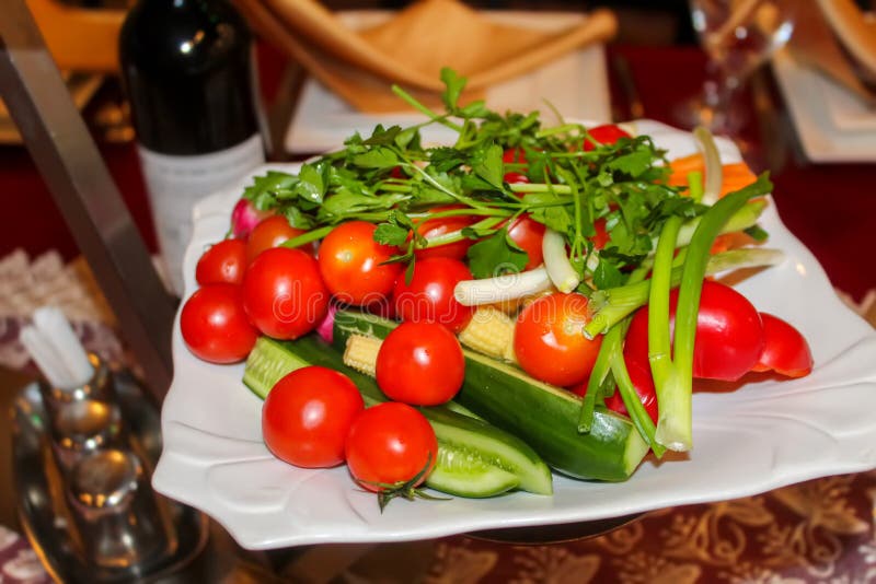 Verse groenten op een schotel in het restaurant: komkommers, kersentomaten, koriander, groene uien, groene paprika's stock fotografie Verse groenten op een schotel in het restaurant: komkommers, kersentomaten, koriander, groene uien, groene paprika's stock fotografie