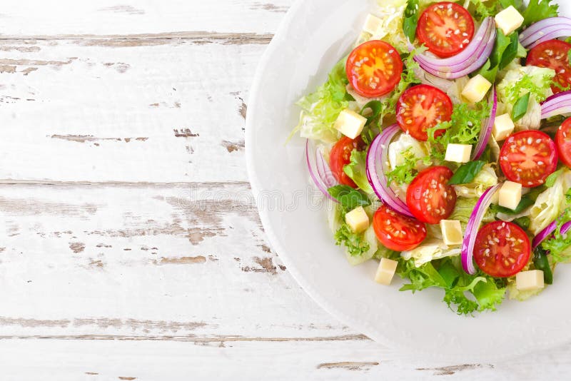 Verse groentesalade met tomaten, sla, ui en kaas op witte houten achtergrond Gezond vegetarisch voedsel royalty-vrije stock afbeelding Verse groentesalade met tomaten, sla, ui en kaas op witte houten achtergrond Gezond vegetarisch voedsel royalty-vrije stock afbeelding