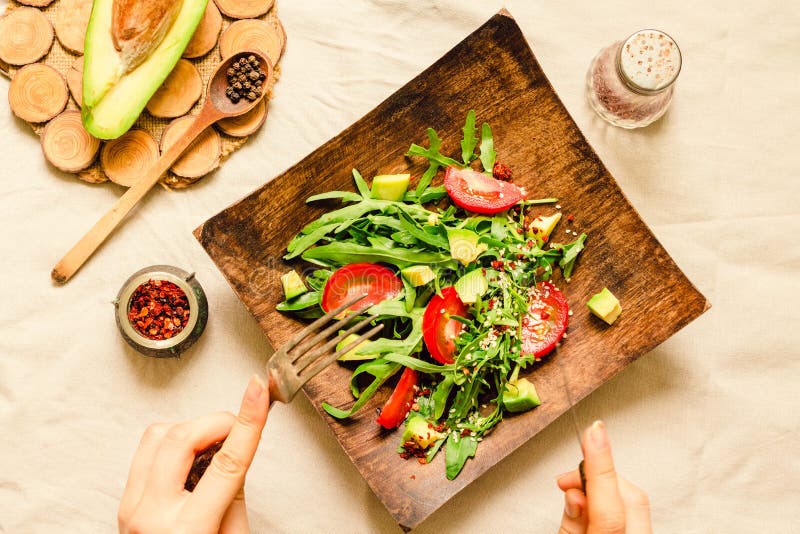 Verse lichtgroene salade met avocado en tomaten in een houten plaat Hoogste mening Het proces om te eten stock foto's Verse lichtgroene salade met avocado en tomaten in een houten plaat Hoogste mening Het proces om te eten stock foto's