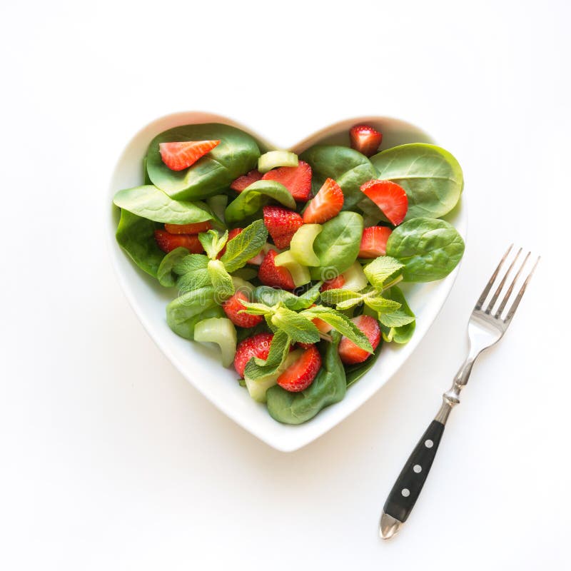 Verse salade van aardbei, selderie, spinazie, pijnboomnoten, kaas in plaat als hart op wit Vierkant beeld Concept het schone eten stock afbeeldingen Verse salade van aardbei, selderie, spinazie, pijnboomnoten, kaas in plaat als hart op wit Vierkant beeld Concept het schone eten stock afbeeldingen