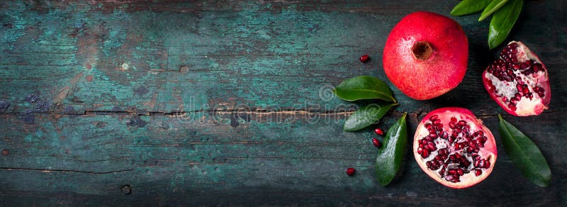 Verse sappige granaatappel - geheel en besnoeiing, met bladeren op een houten uitstekende achtergrond, hoogste horizontale mening