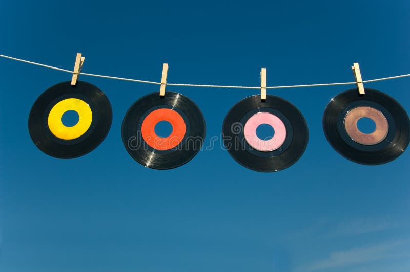 45 rpnm records handing from a clothesline against a bright blue sky, insert text on label. 45 rpnm records handing from a clothesline against a bright blue sky, insert text on label