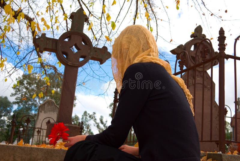 Veiled Woman Places Flower on Grave. Veiled Woman Places Flower on Grave