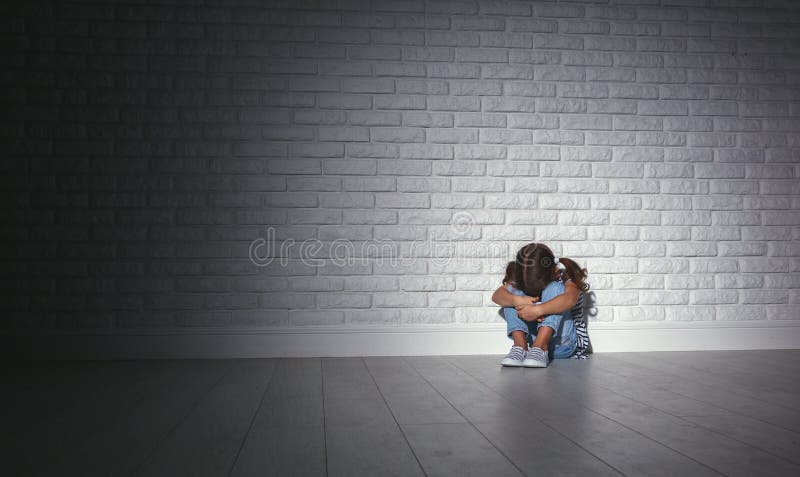 Verstoor droevig droevig kindmeisje in spanningsschreeuwen bij een lege donkere muur