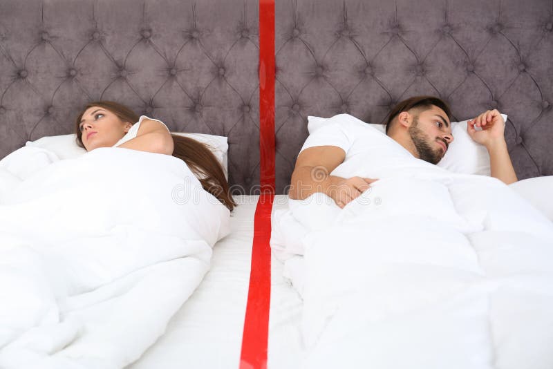 Verstoor jong paar met verhoudingsproblemen die afzonderlijk in bed liggen stock afbeelding Verstoor jong paar met verhoudingsproblemen die afzonderlijk in bed liggen stock afbeelding
