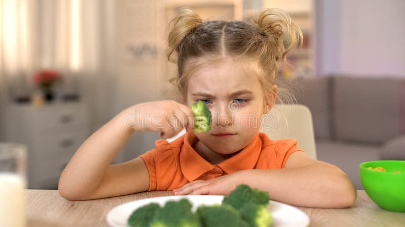 Verstoord meisje die broccoli met afschuw, volledig van vitaminen maar smaakloos voedsel bekijken stock afbeeldingen Verstoord meisje die broccoli met afschuw, volledig van vitaminen maar smaakloos voedsel bekijken stock afbeeldingen