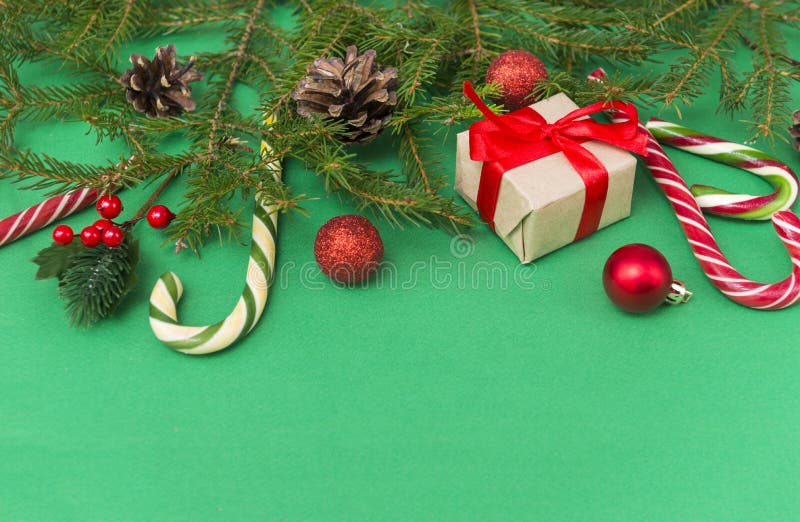 Vertakkingen op een groene achtergrond, een cadeaudoos met een rood lint, kegels, kaneelstokken, lolly's, een stukje gedroogd ora stock afbeelding Vertakkingen op een groene achtergrond, een cadeaudoos met een rood lint, kegels, kaneelstokken, lolly's, een stukje gedroogd ora stock afbeelding