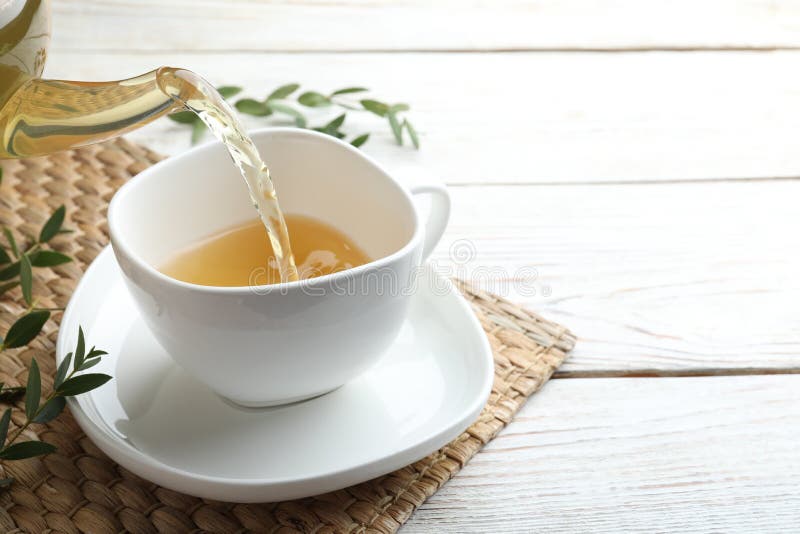 Verter té de eucalipto aromático en la taza en la mesa de madera blanca. espacio para texto