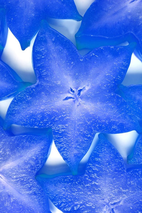 Verticaal Beeld van de Rijpe Verse Plakken van het Sterfruit in Levendig Blauw voor Achtergrond royalty-vrije stock foto Verticaal Beeld van de Rijpe Verse Plakken van het Sterfruit in Levendig Blauw voor Achtergrond royalty-vrije stock foto