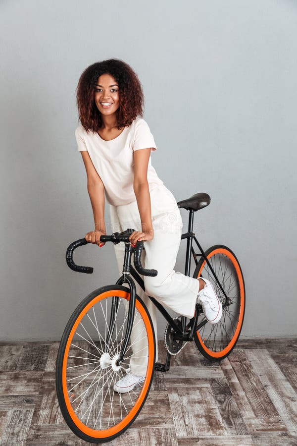 Verticaal beeld van vrij Glimlachende Afrikaanse vrouw die op fiets berijdt stock foto Verticaal beeld van vrij Glimlachende Afrikaanse vrouw die op fiets berijdt stock foto