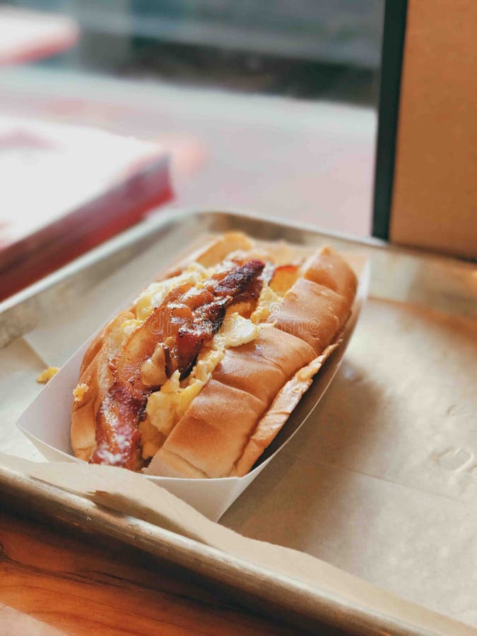 Verticaal schot van een heerlijk ei- en baconbroodje op een metalen bakje stock afbeelding Verticaal schot van een heerlijk ei- en baconbroodje op een metalen bakje stock afbeelding