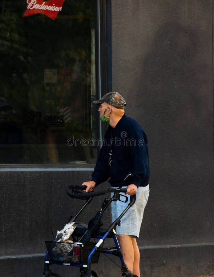 Vertical closeup of an old man looking inside a store through a window, holding a luggage trolley royalty free stock photo