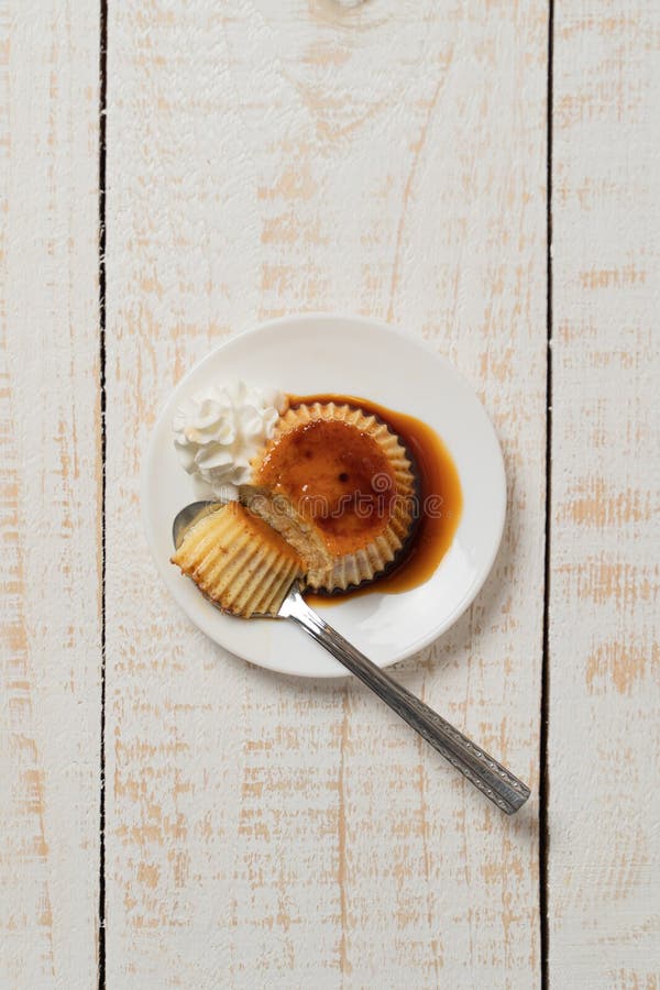 Vertical Closeup of a Plate of Creme Caramel Dessert on the White Plank