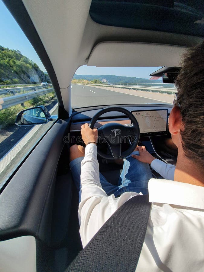 VERTICAL: Commuter drives down the empty highway in a high tech Tesla vehicle. royalty free stock images