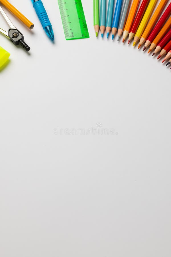 Vertical composition of colorful crayons and other school tools on white surface with copy space. School equipment, tools, learning and creativity concept.