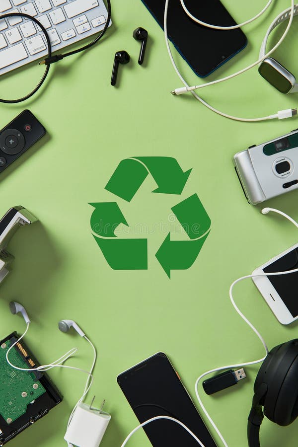 Vertical flat lay of obsolete electronic devices and gadgets framing a green recycling symbol on a g royalty free stock images