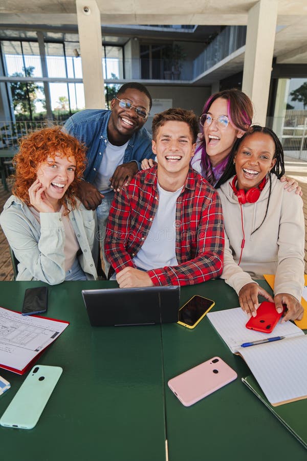 Vertical. groupe multiracial souriant de jeunes étudiants regardant la caméra assis ensemble dans la bibliothèque universitaire av photos stock