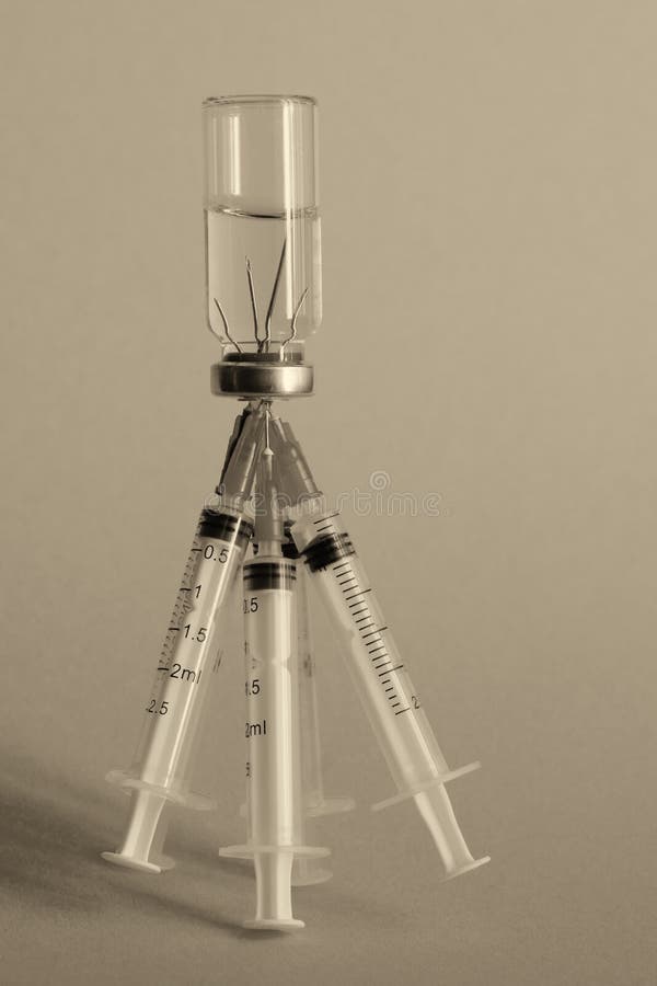 A Vertical Image of a Medicine Bottle and Five Syringes Sticking Out of