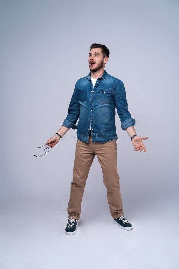 Vertical image of shocked man in shirt and jeans. Isolated on gray background. royalty free stock photography Vertical image of shocked man in shirt and jeans. Isolated on gray background. royalty free stock photography
